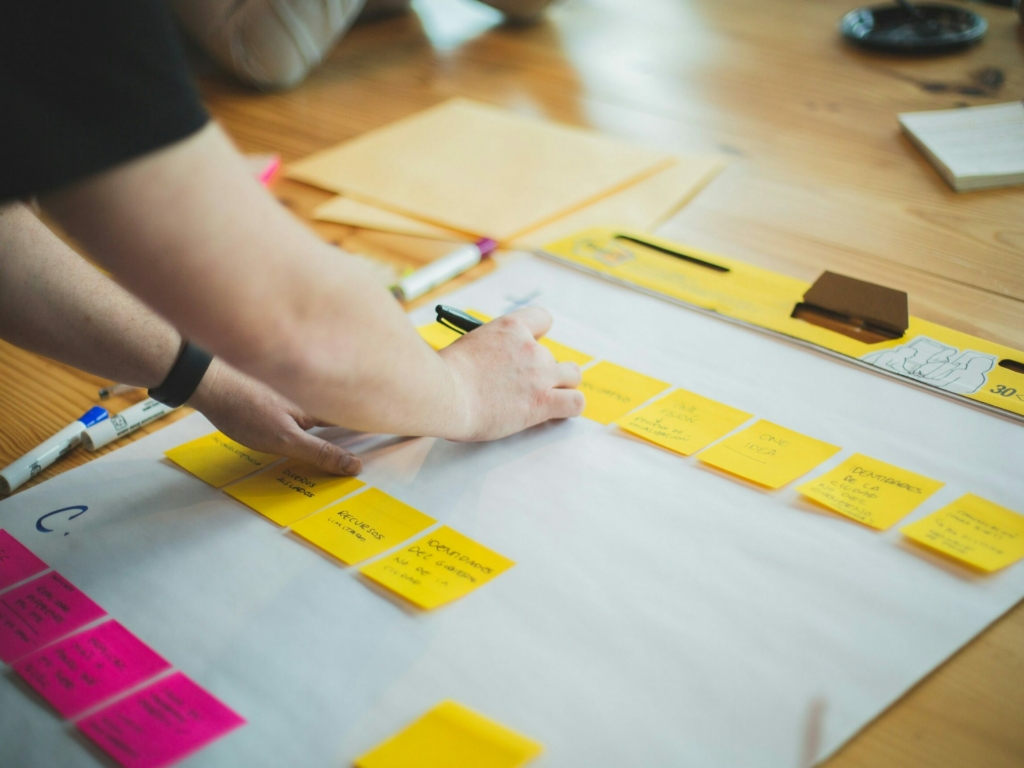 Photographie d'une personne faisant une liste de post-its de compétences qu'elle a acquis durant son parcours professionnel.