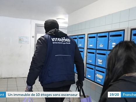 Capture d'écran d'un reportage publié par France 3 au sujet d'un immeuble en panne d'ascenseur à Besançon. On voit sur cette image un des salariés d'INTERMED aider une résidente à porter ses courses.